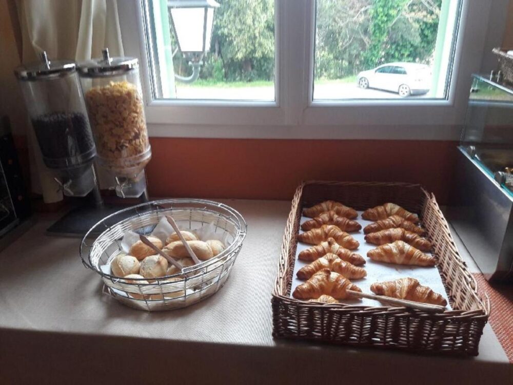 Petit-déjeuner avec croissants et céréales près d'une fenêtre.