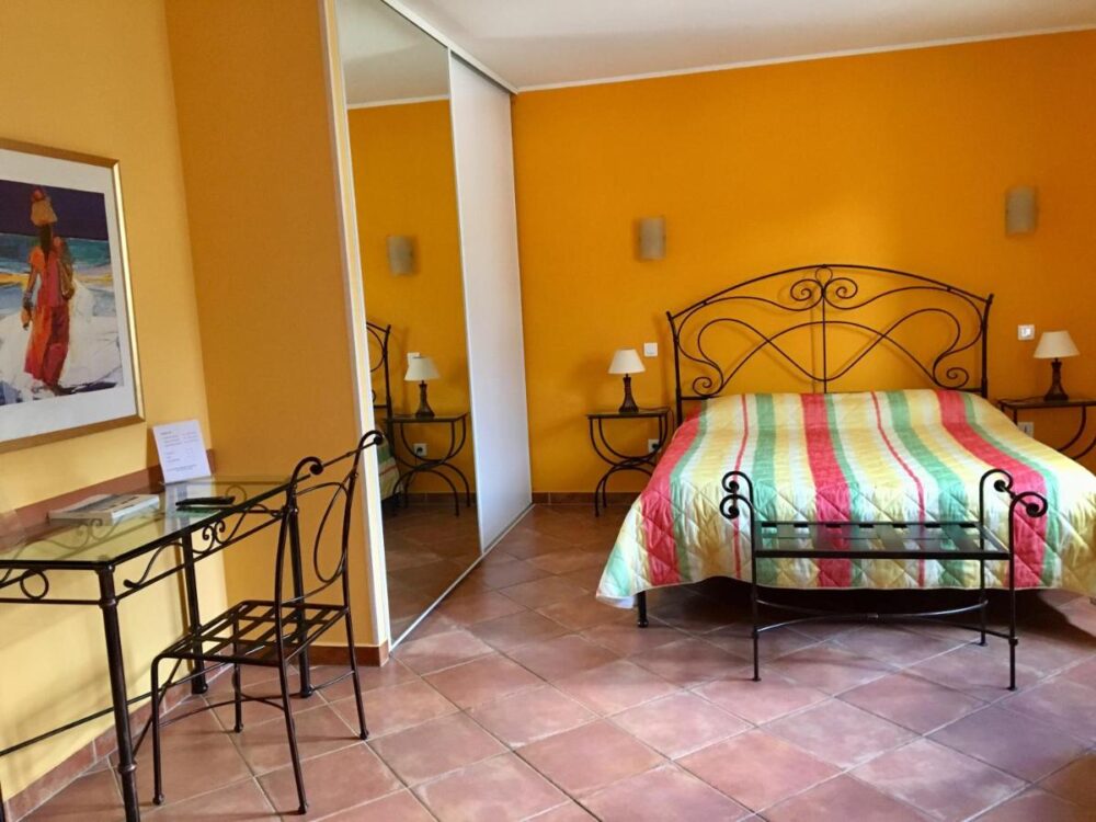 Chambre lumineuse avec lit double et décoration colorée.
