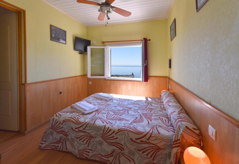 Chambre avec vue sur mer depuis fenêtre ouverte.