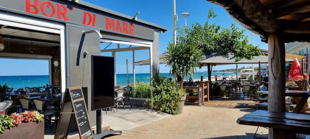 Terrasse de restaurant en bord de mer ensoleillé.