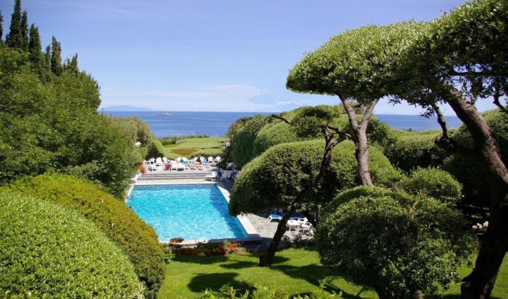 Piscine entourée de verdure face à la mer.