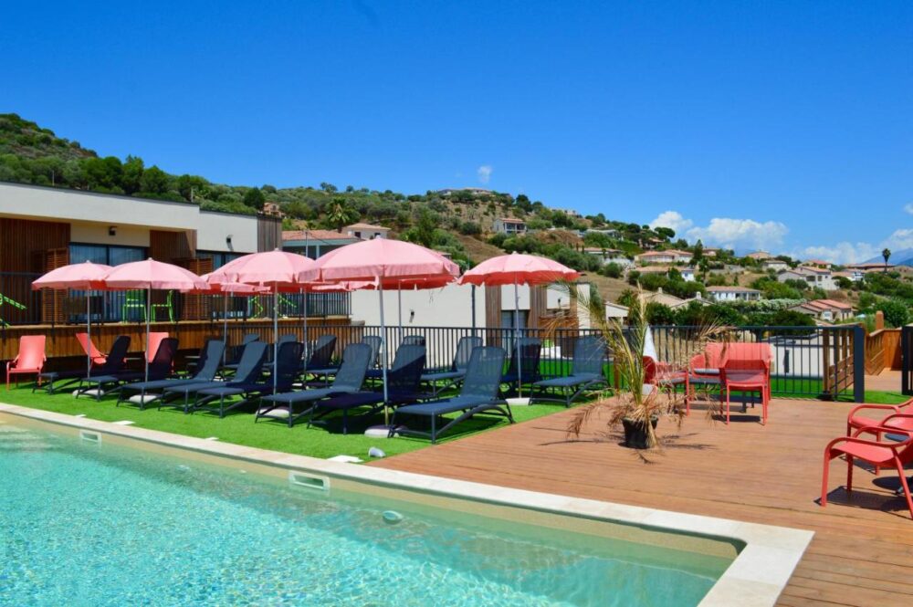 Piscine avec transats et parasols roses.