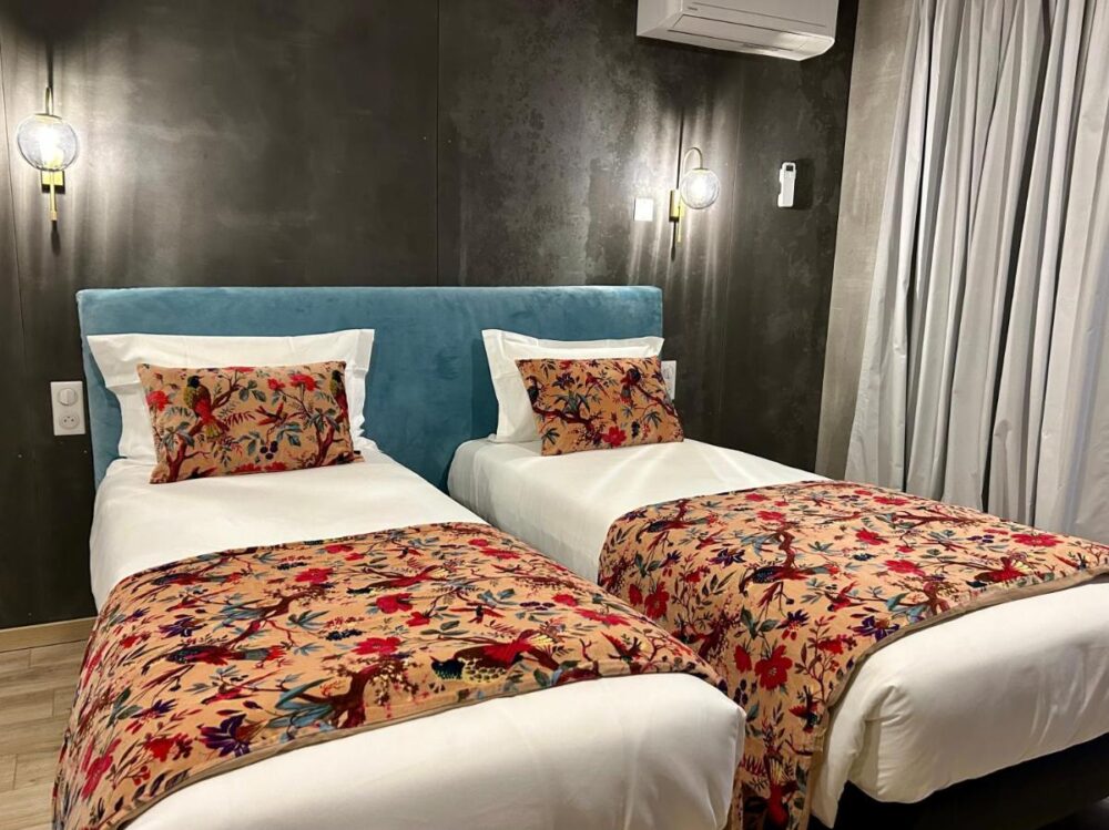 Chambre avec deux lits et décor floral.