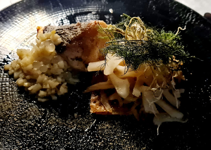 Plat gastronomique avec poisson et légumes variés.