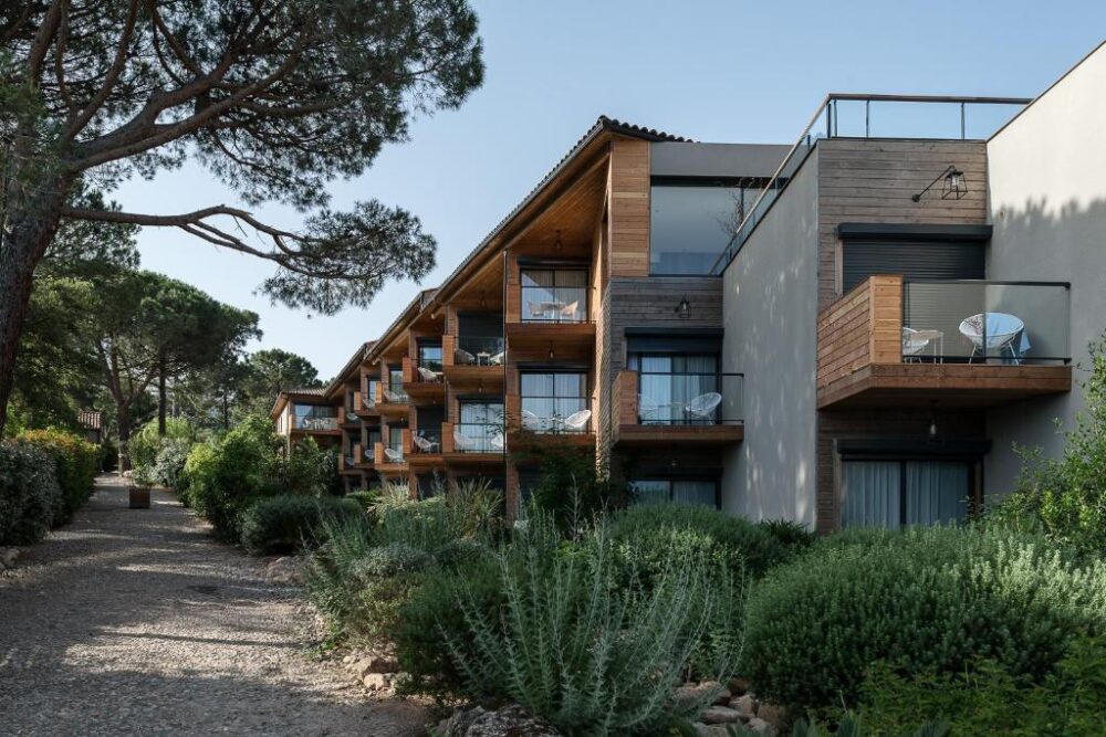 Bâtiment moderne entouré de verdure et de pins.