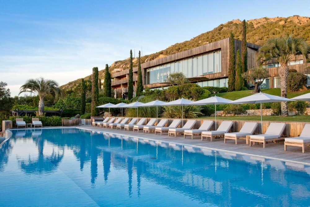 Piscine luxueuse avec chaises longues et parasols.