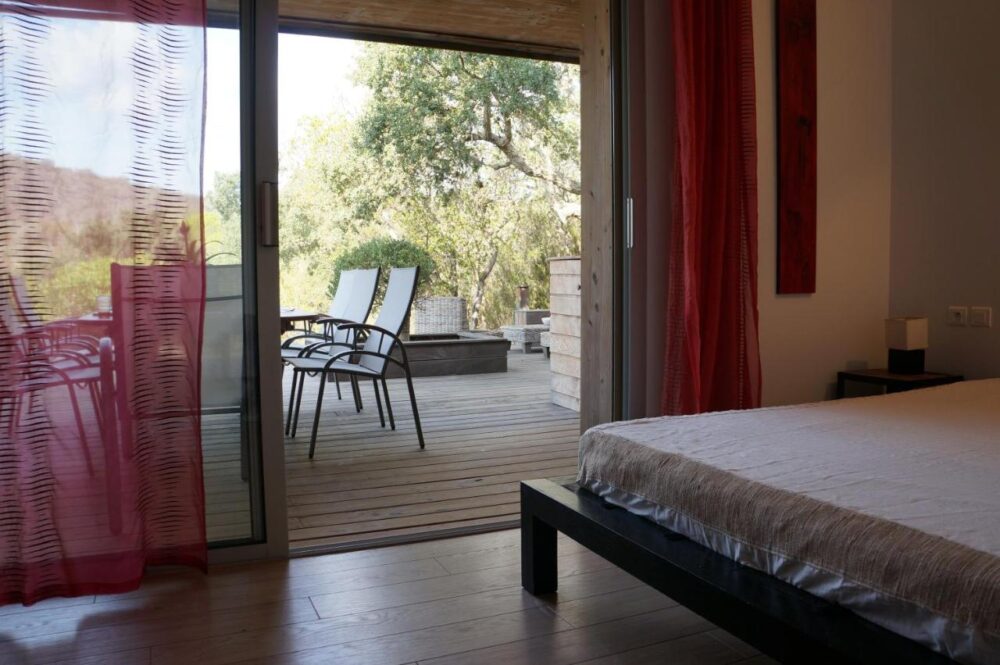 Chambre avec terrasse en bois et chaises longues.
