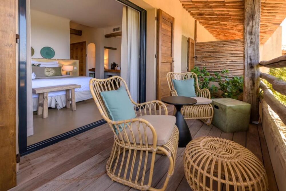 Terrasse avec fauteuils, table, vue chambre ouverte.