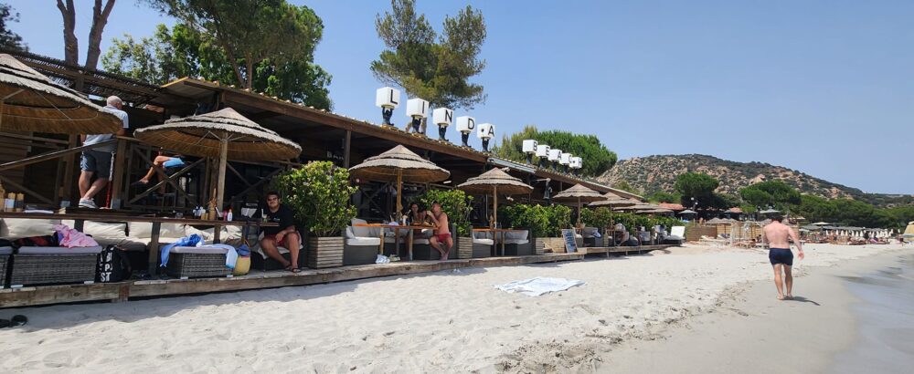 Plage avec chaises longues et parasols en bois.