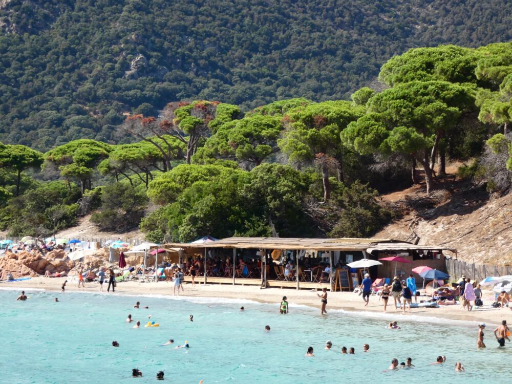 Plage animée avec cabane et baigneurs.