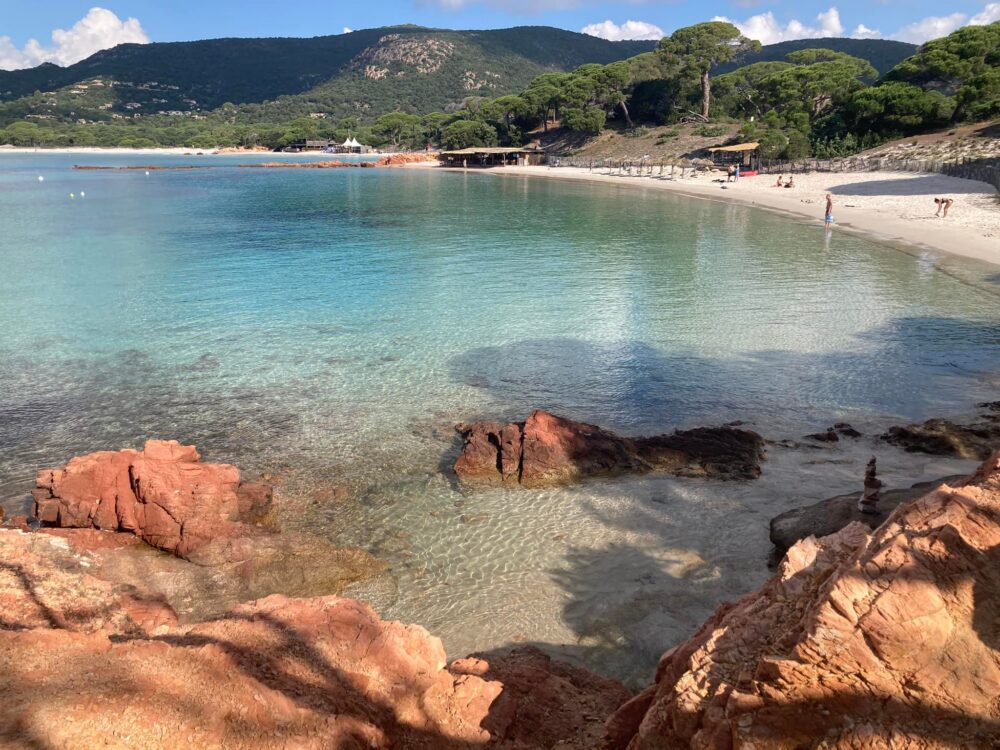 Plage avec eau turquoise et rochers rouges