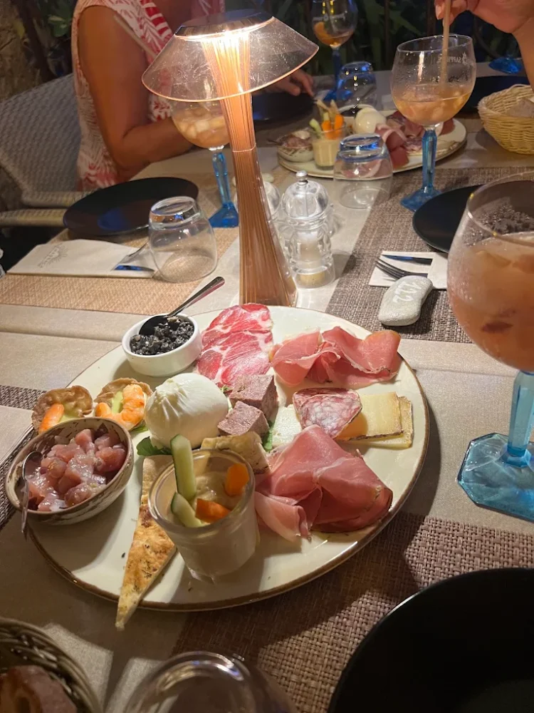 Plateau de charcuterie et fromages sur table éclairée.