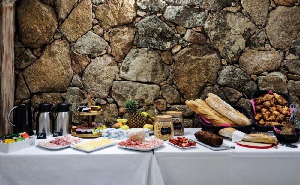 Buffet de petit-déjeuner varié devant mur en pierre.