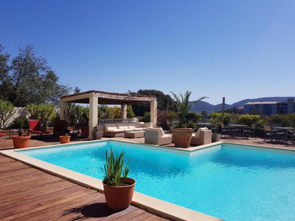 Piscine extérieure avec chaises longues et parasol.