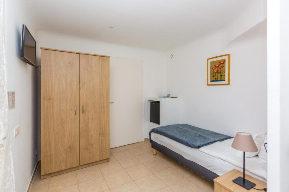 Petite chambre avec lit simple et armoire bois