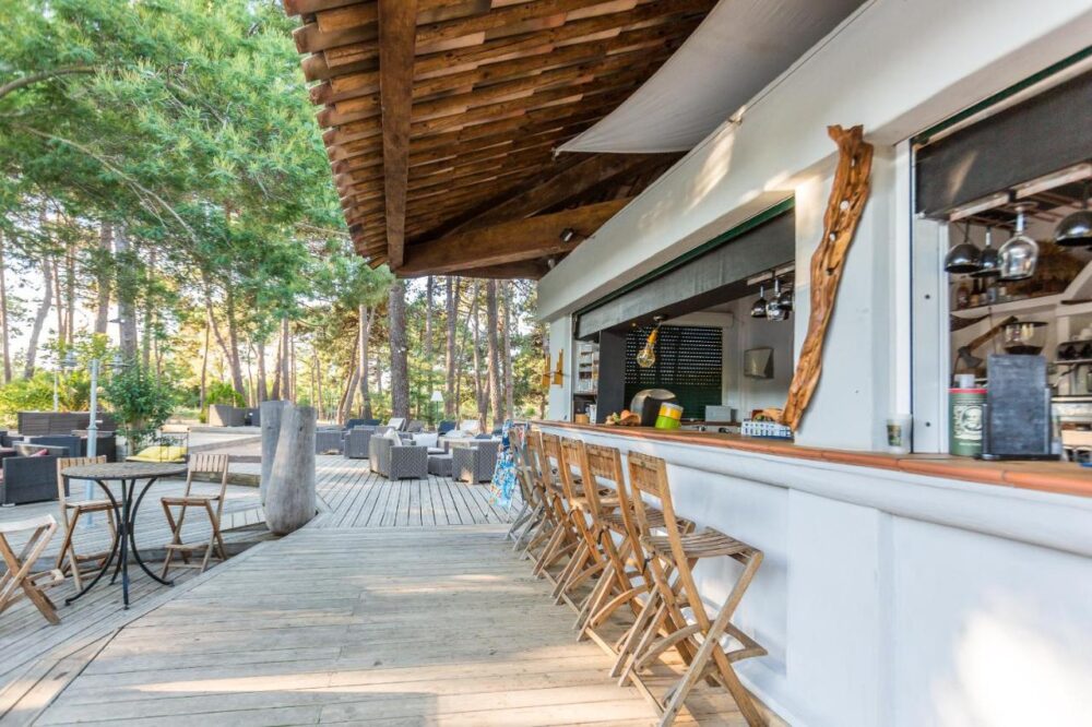 Terrasse extérieure en bois d'un café ombragé.