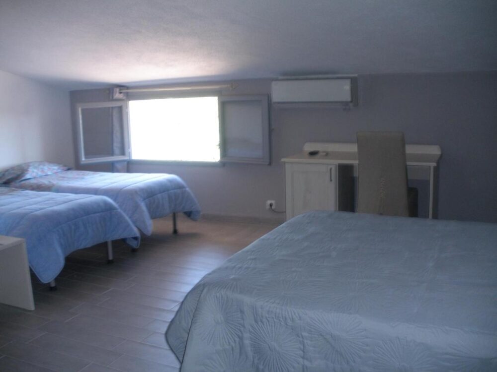 Chambre à trois lits avec bureau et fenêtre.