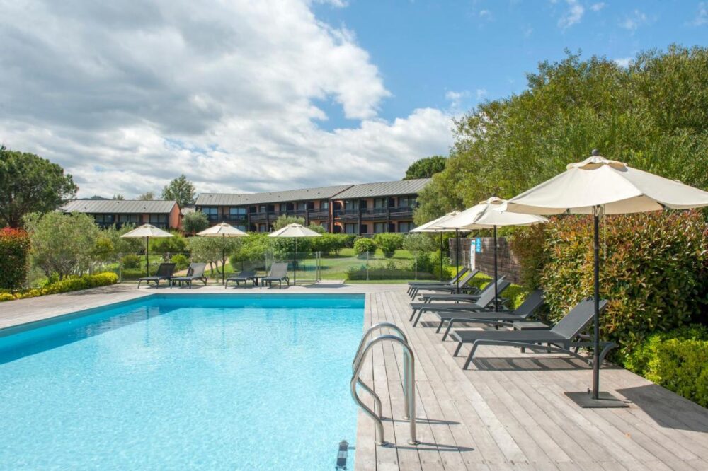 Piscine extérieure avec chaises longues et parasols.
