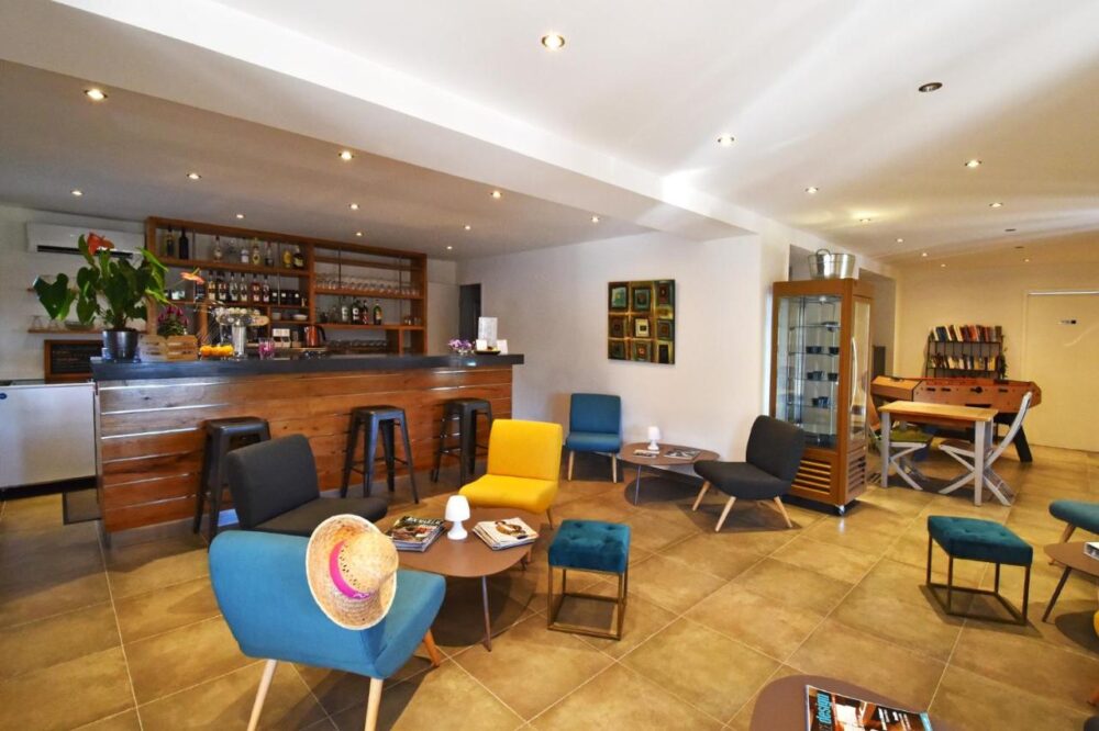 Salle avec bar, sièges colorés et baby-foot.