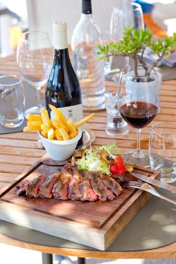 Repas avec viande, frites et vin rouge.