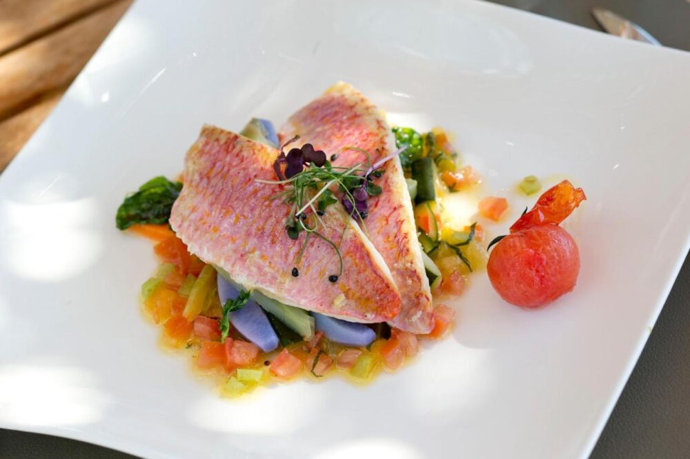 Plat raffiné avec poisson et légumes colorés.