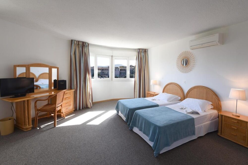 Chambre d'hôtel avec lits jumeaux et bureau.