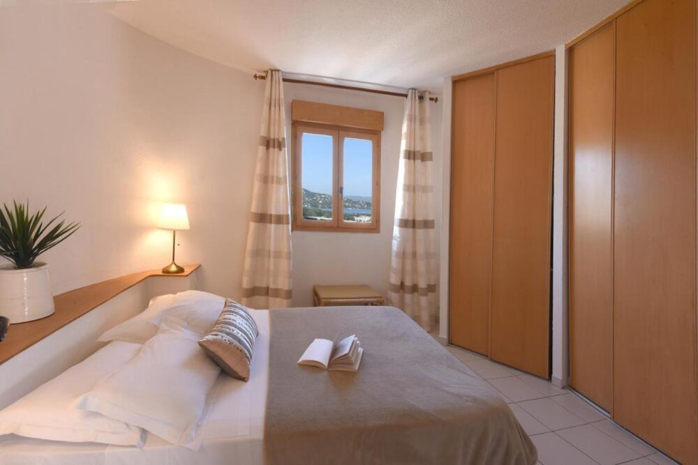 Chambre lumineuse avec fenêtre et placards en bois.