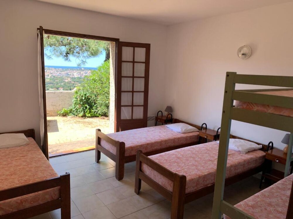 Chambre avec lits simples, vue sur jardin méditerranéen.