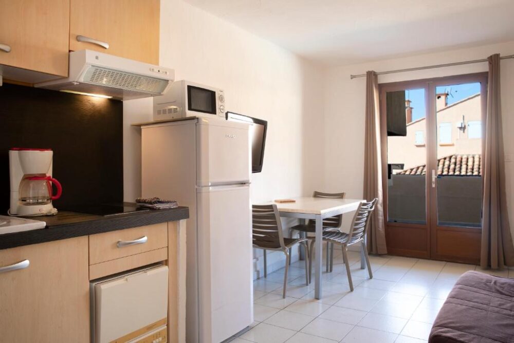 Cuisine moderne avec table et fenêtres ouvertes.