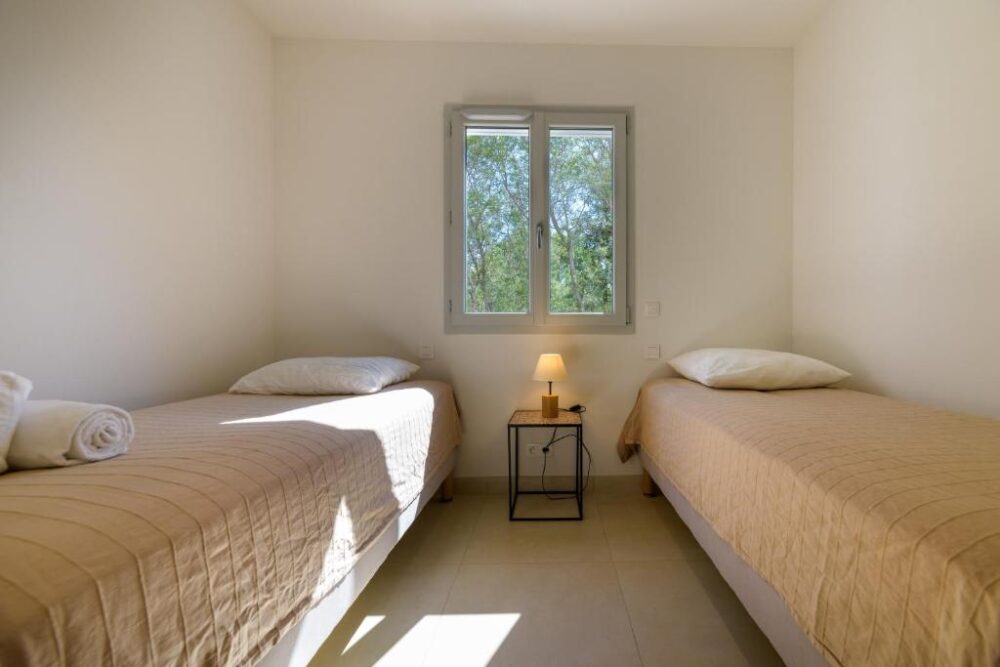 Chambre avec deux lits simples et lampe.