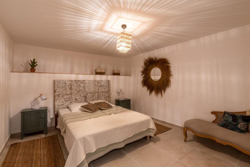 Chambre moderne avec lit, miroir et chaise longue.