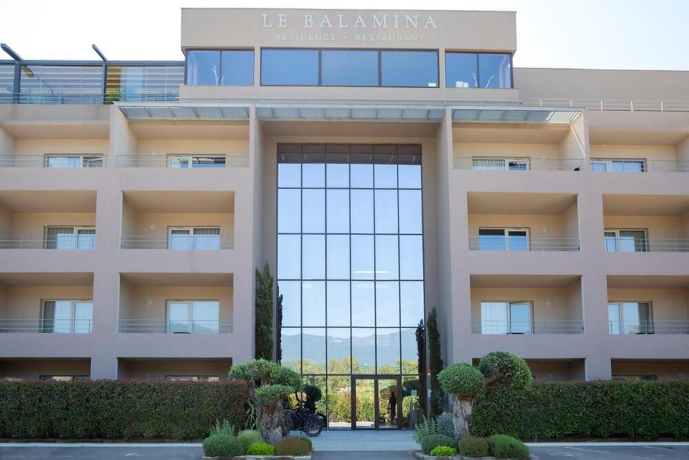 Façade d'un hôtel moderne avec balcons et vitres.