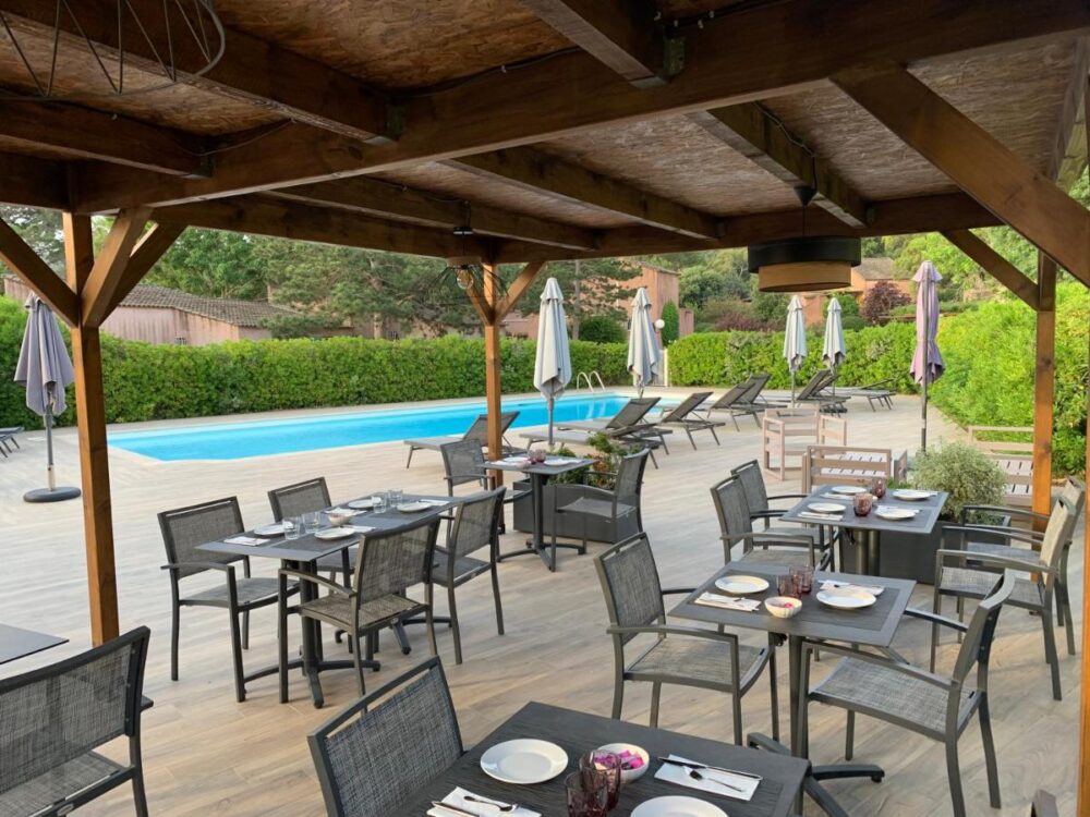 Terrasse avec tables près d'une piscine.