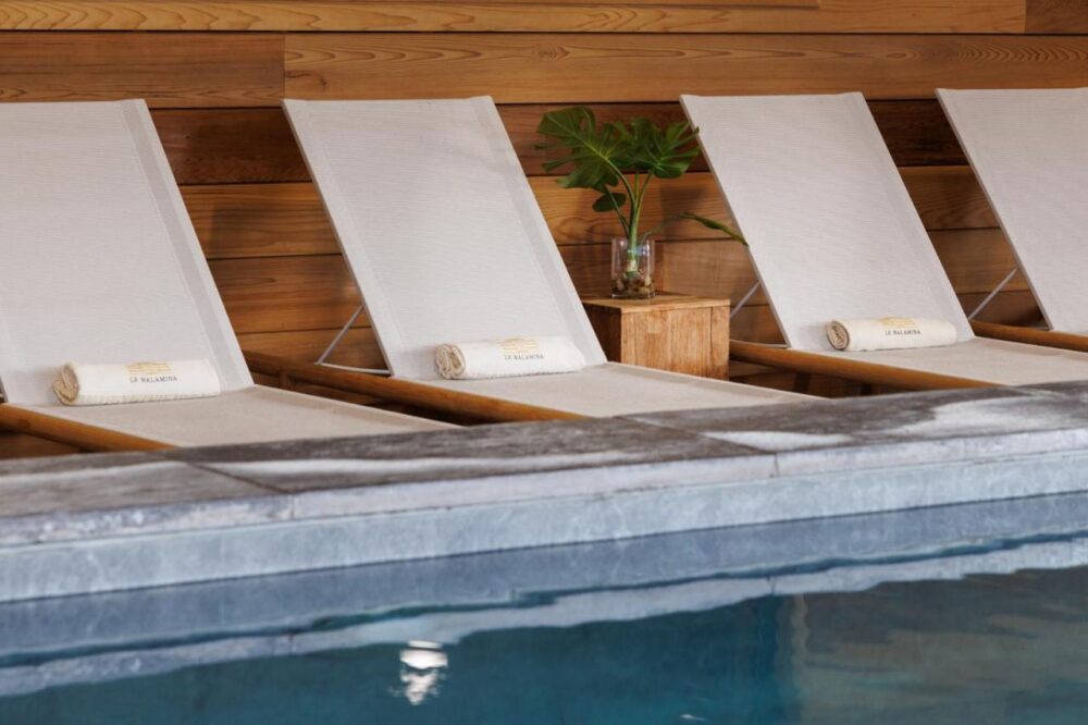 Chaises longues blanches au bord d'une piscine.