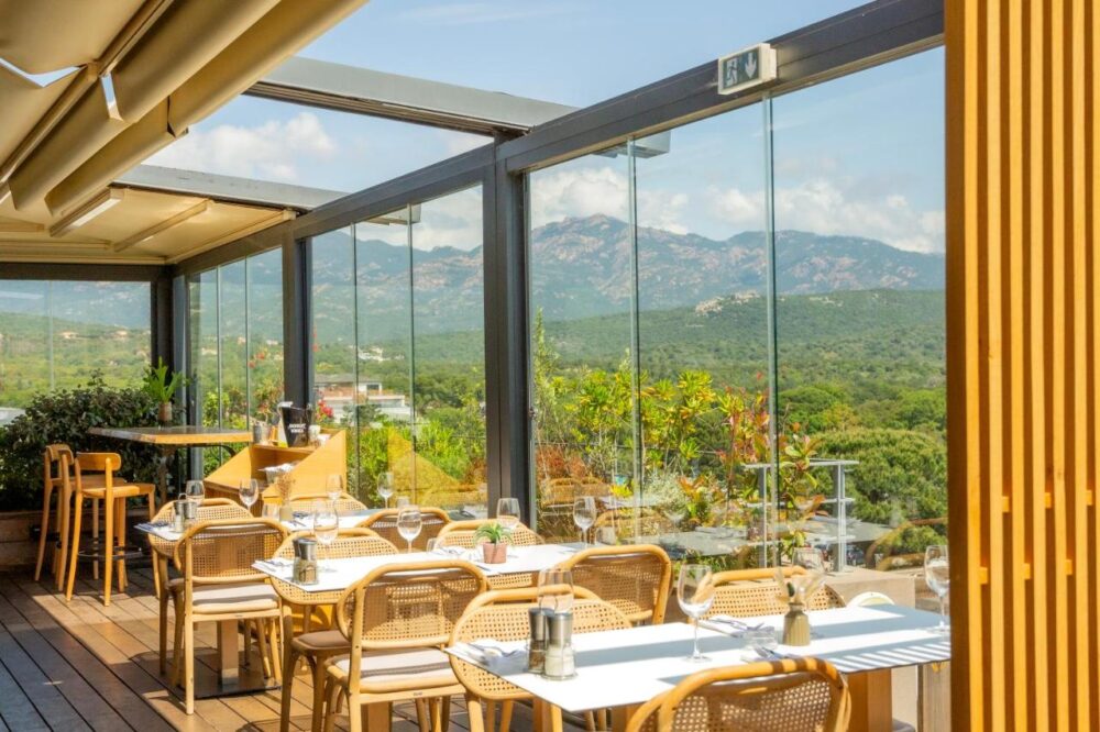 Terrasse de restaurant avec vue sur montagnes verdoyantes.