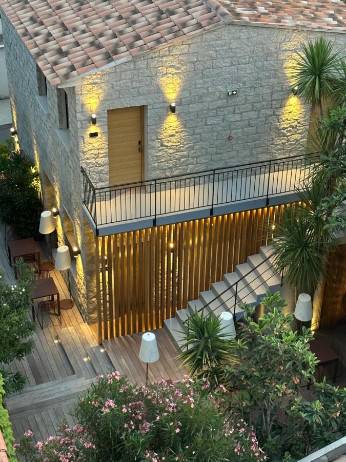 Maison en pierre éclairée, escalier extérieur et plantes.