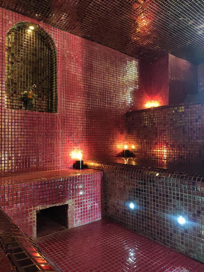 Hammam moderne, mosaïque rouge, lumière tamisée.