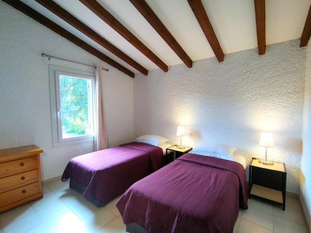 Chambre avec deux lits simples et lampe.