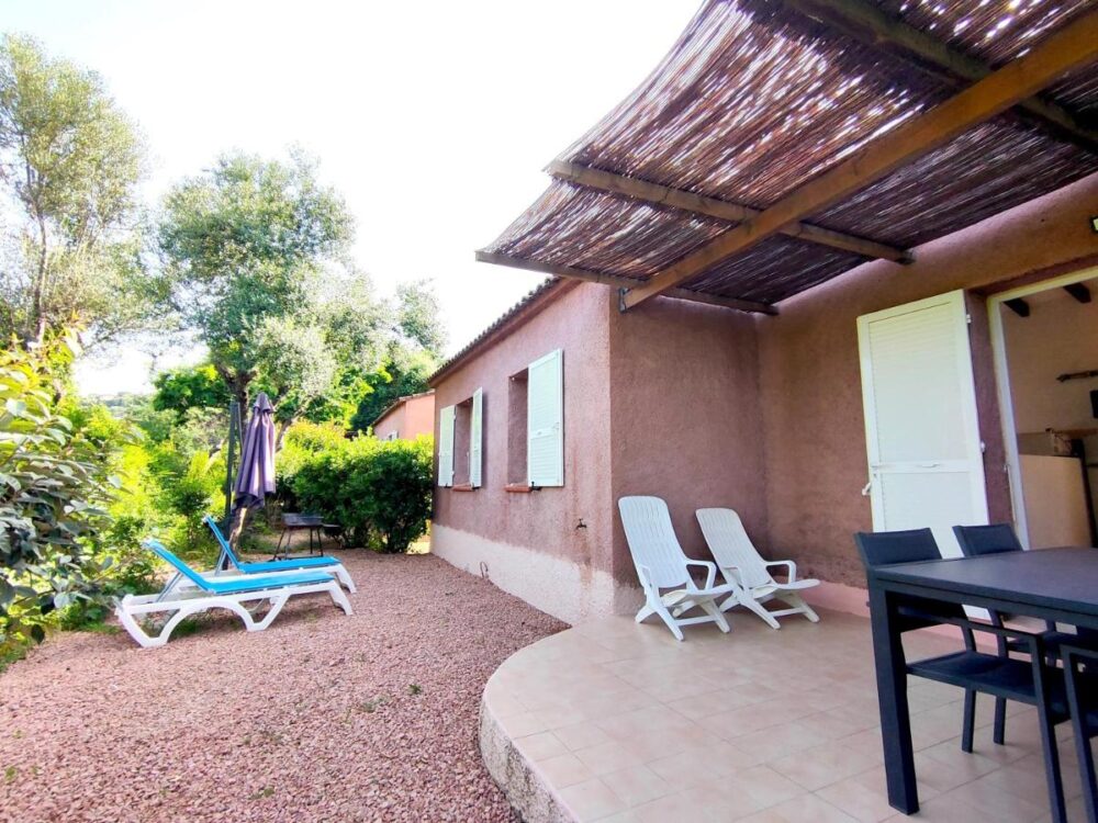 Jardin avec chaises longues et table sur terrasse.