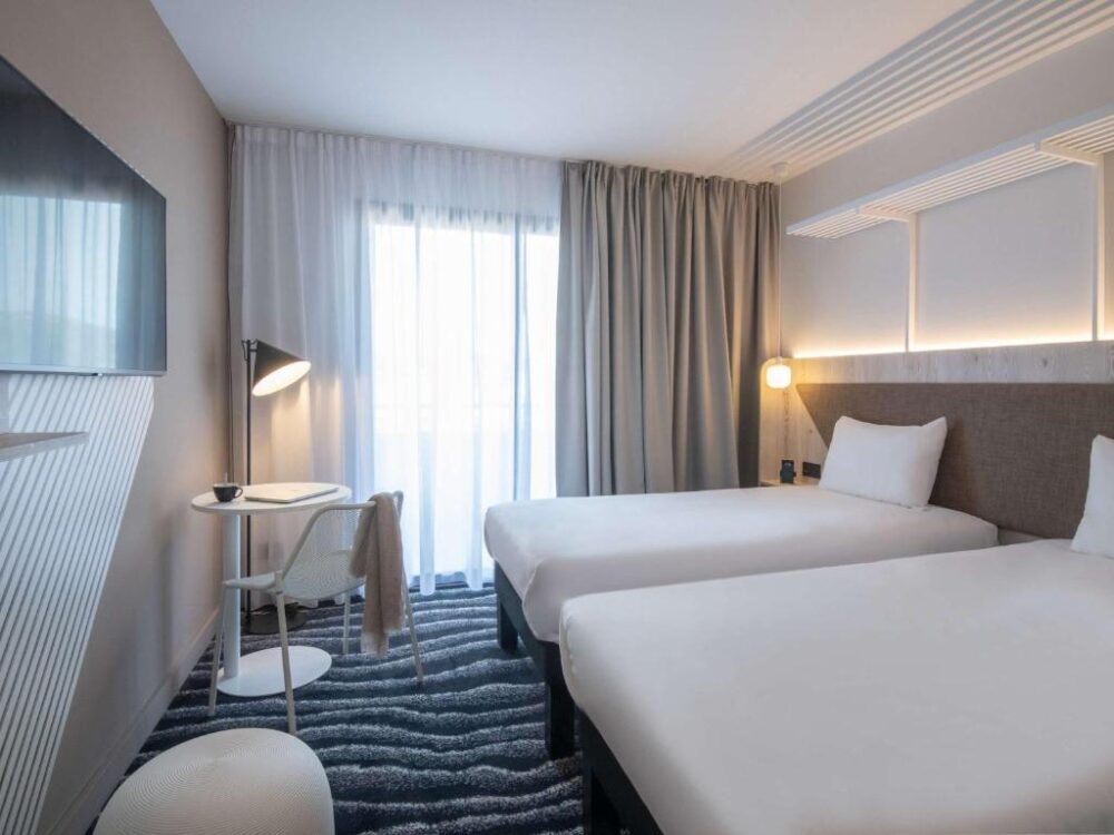 Chambre d'hôtel moderne avec deux lits blancs.