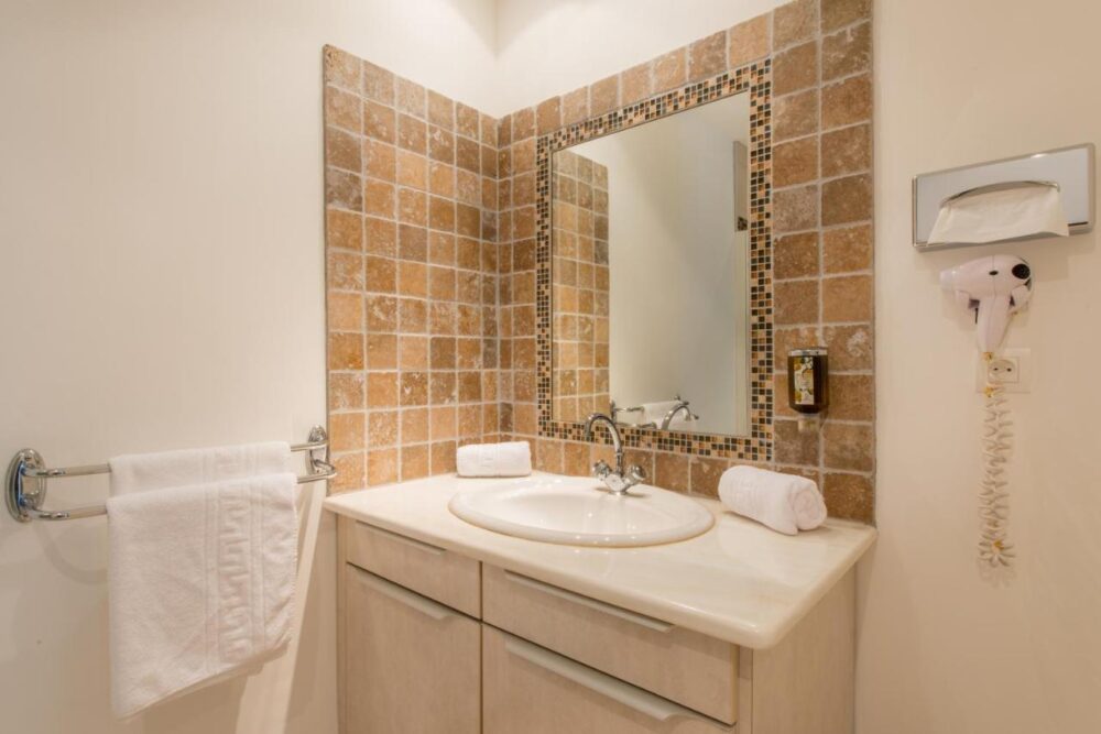 Salle de bain avec lavabo et miroir carrelé.