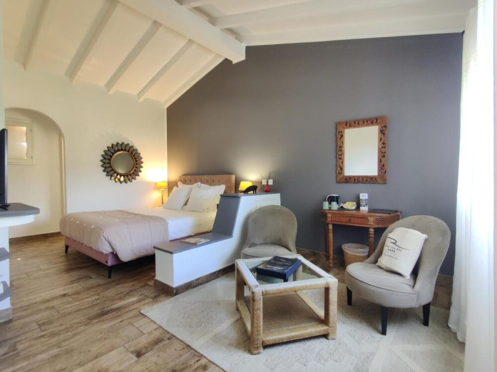 Chambre d'hôtel lumineuse avec lit et fauteuils.