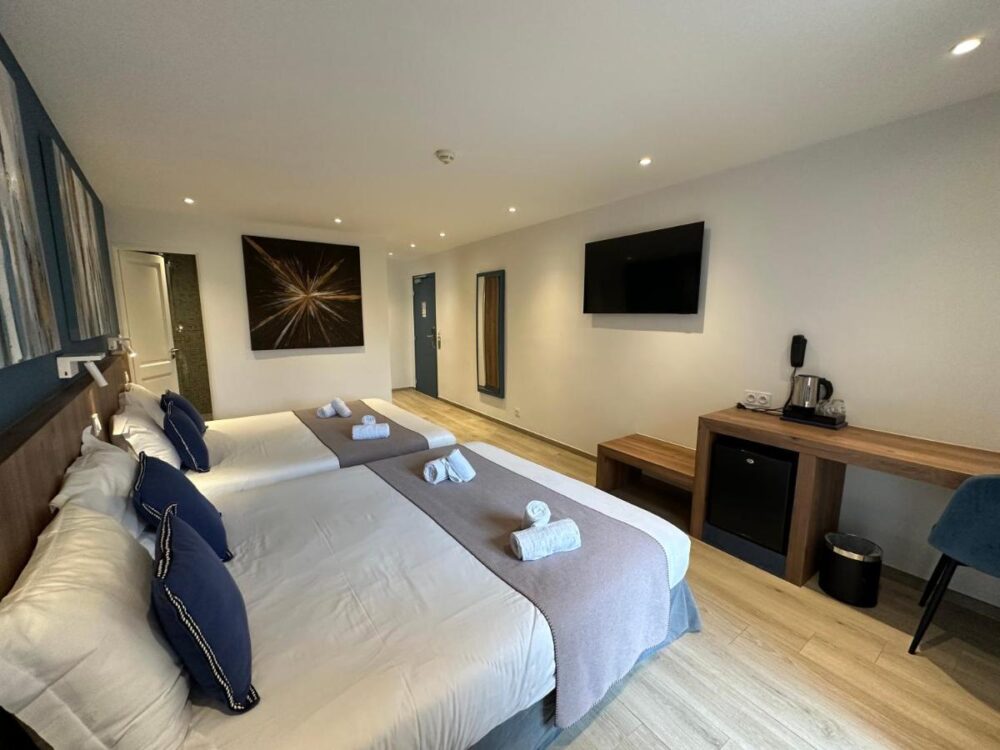 Chambre d'hôtel moderne avec deux lits doubles.