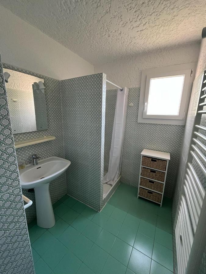 Salle de bain avec douche et lavabo blancs.