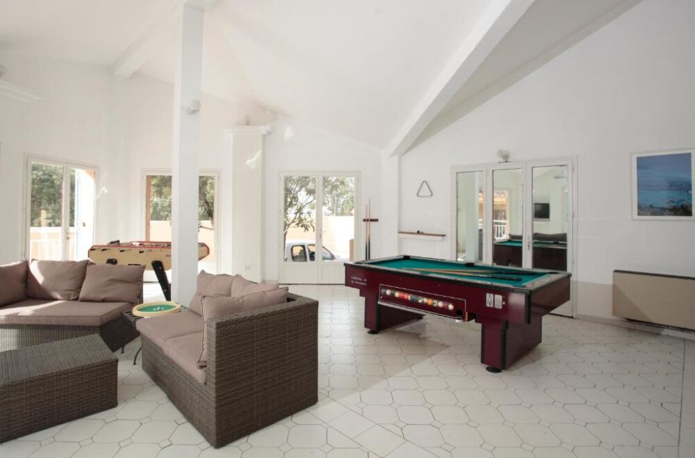 Salle de jeux avec billard et canapés.