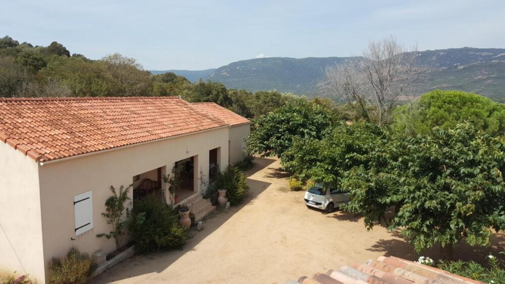 Maison avec toit en tuiles et paysages montagneux.