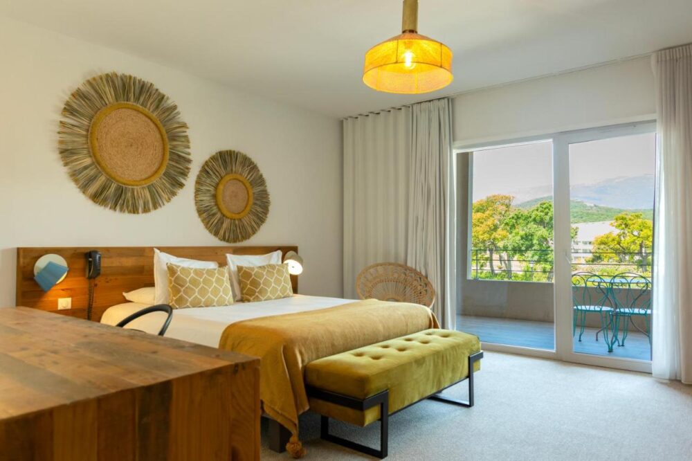 Chambre lumineuse avec vue sur terrasse et nature.