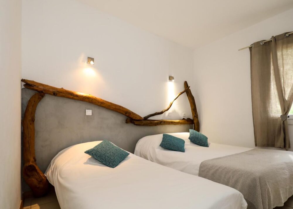 Chambre avec deux lits simples et décoration en bois.