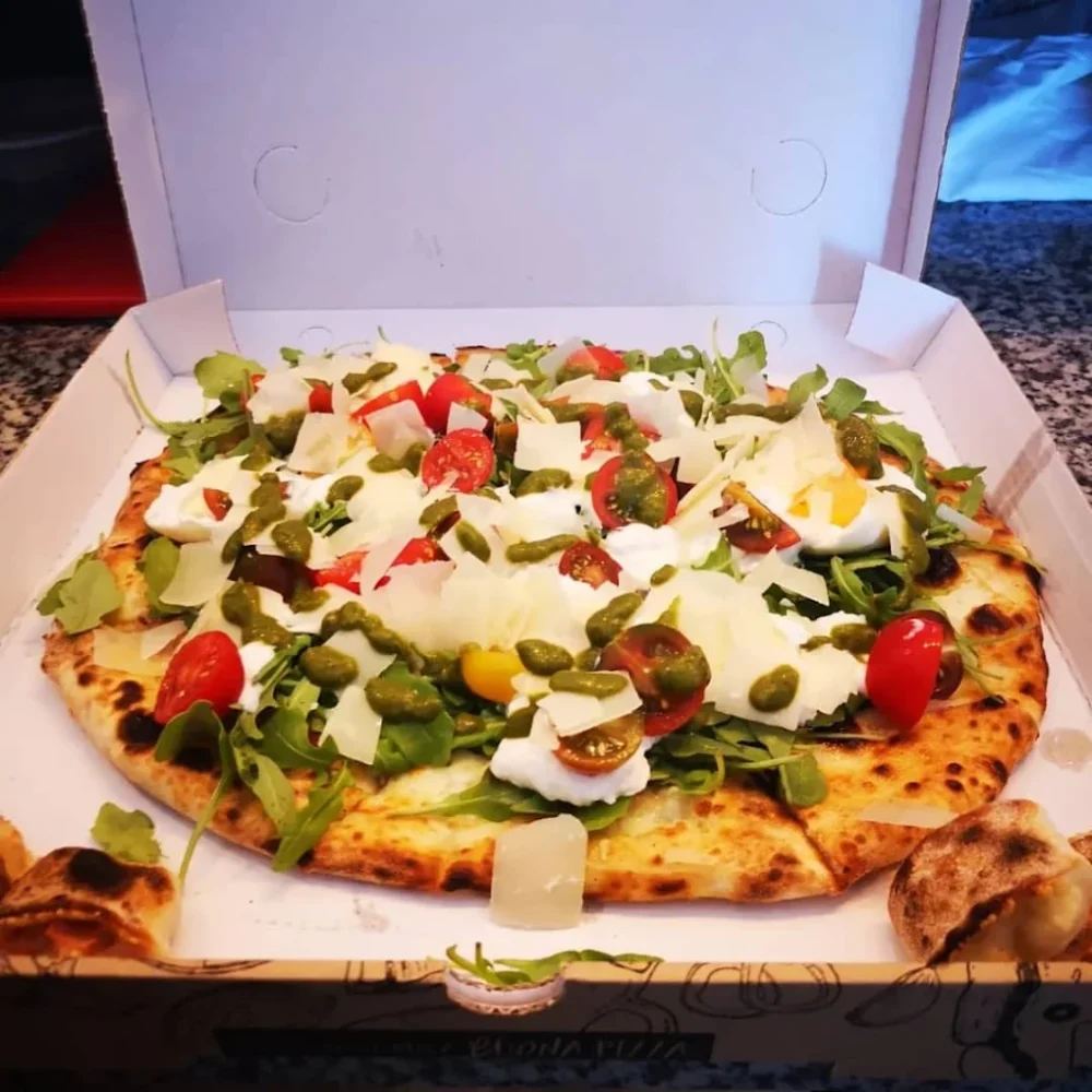 Pizza garnie de légumes et fromage dans une boîte.