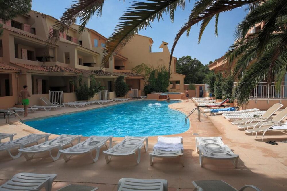Piscine extérieure entourée de chaises longues vides.